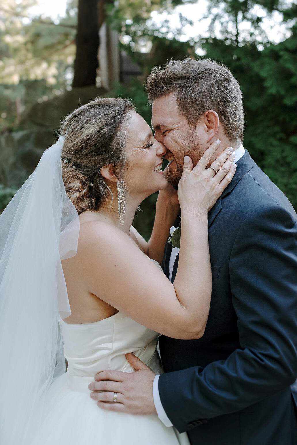 Bride and Groom portrait while they are kissing and laughing.